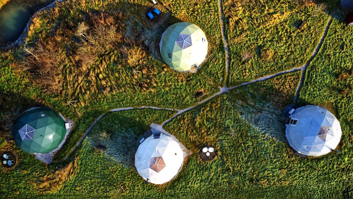 Dôme géodésique dans une prairie belge au soleil couchant